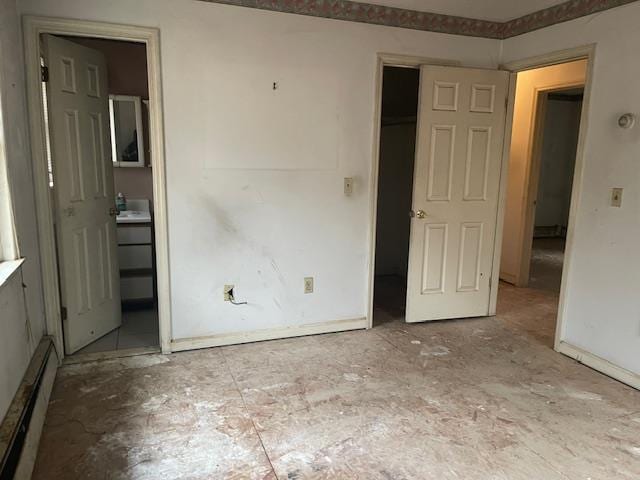 unfurnished bedroom featuring connected bathroom and a baseboard radiator