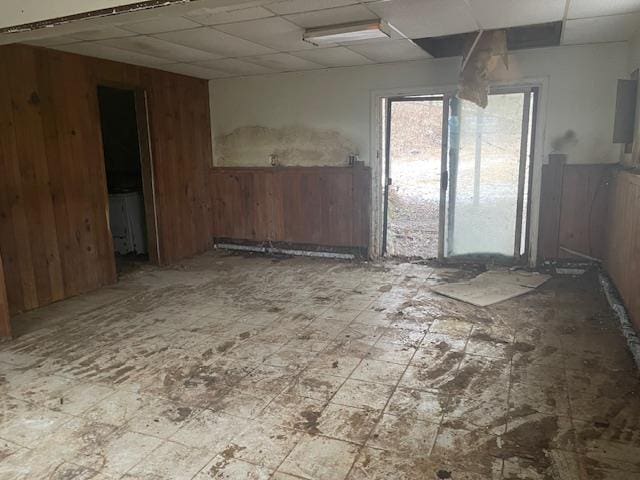 spare room featuring a drop ceiling and wood walls