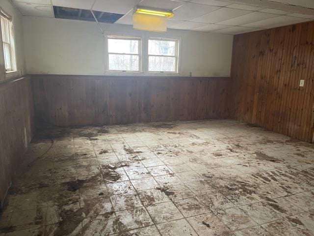 basement featuring a drop ceiling and wood walls