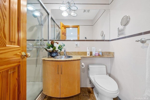 bathroom featuring walk in shower, tile patterned floors, toilet, vanity, and tile walls