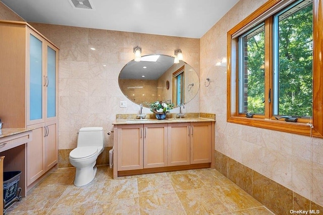 bathroom with vanity, toilet, and tile walls