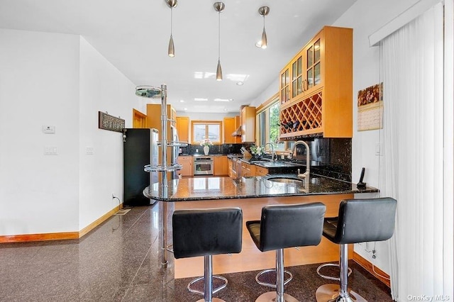 kitchen with a kitchen breakfast bar, sink, hanging light fixtures, appliances with stainless steel finishes, and kitchen peninsula