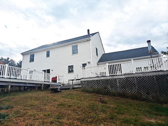 back of house with a deck and a lawn