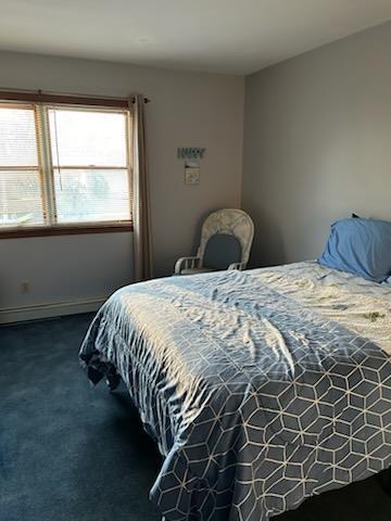 bedroom with dark colored carpet and baseboard heating