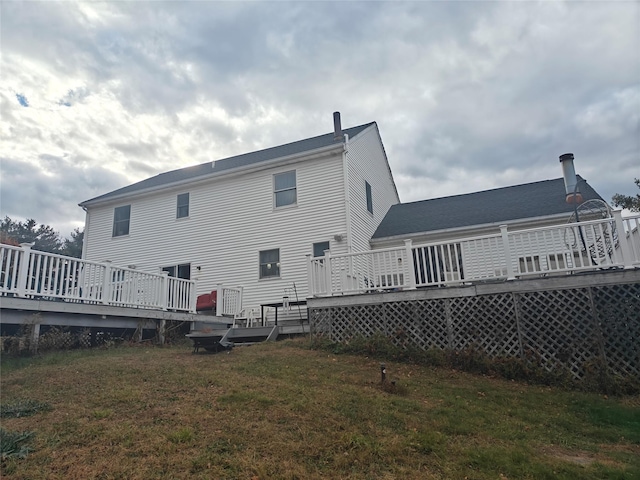 rear view of house featuring a wooden deck and a yard