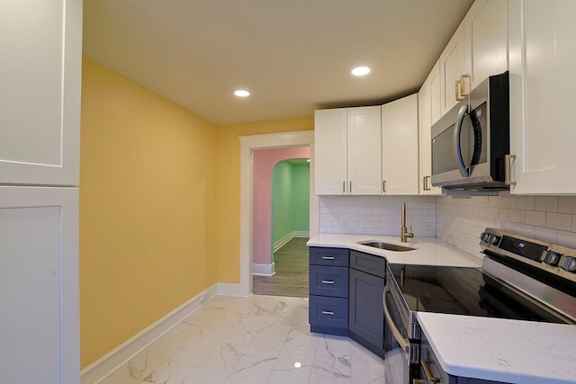 kitchen featuring sink, stainless steel appliances, light stone counters, backsplash, and white cabinets