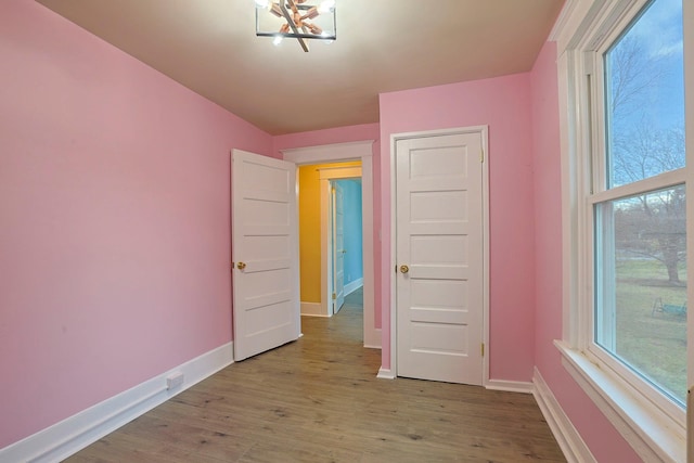 unfurnished bedroom featuring a notable chandelier and light wood-type flooring