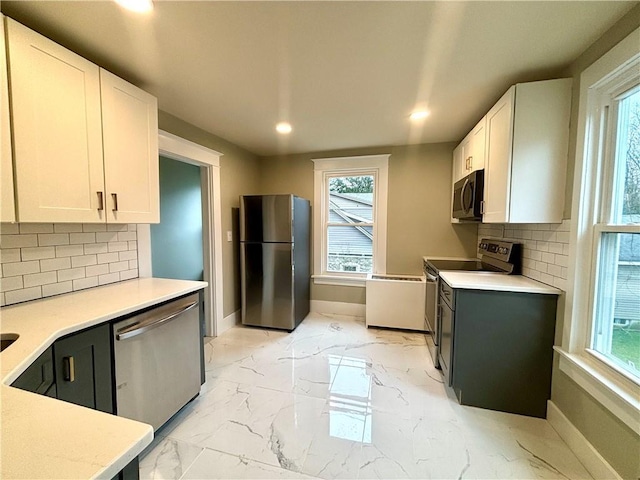 kitchen with stainless steel appliances, white cabinetry, and tasteful backsplash