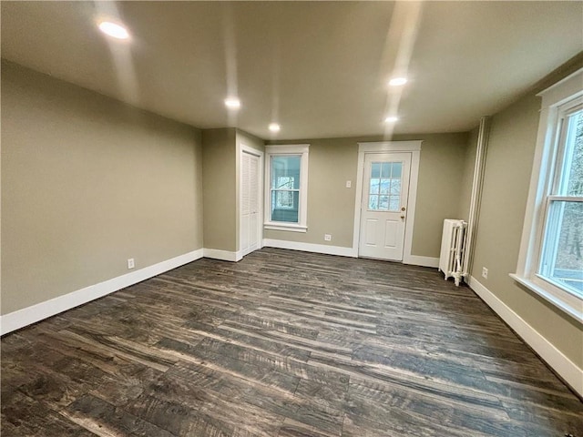 unfurnished room with dark hardwood / wood-style flooring and radiator heating unit