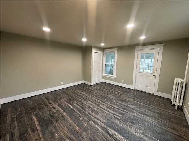 empty room with radiator and dark hardwood / wood-style floors