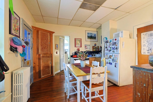 dining area featuring a paneled ceiling, dark hardwood / wood-style floors, and radiator heating unit