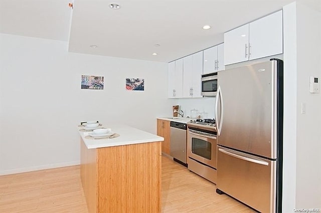 kitchen featuring white cabinets, appliances with stainless steel finishes, light wood-type flooring, and a kitchen island