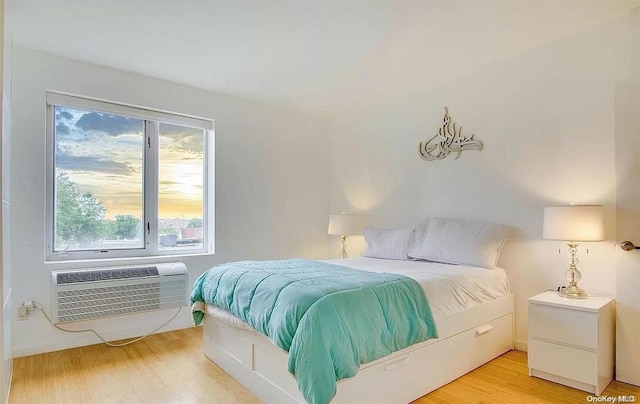 bedroom featuring light wood-type flooring and an AC wall unit