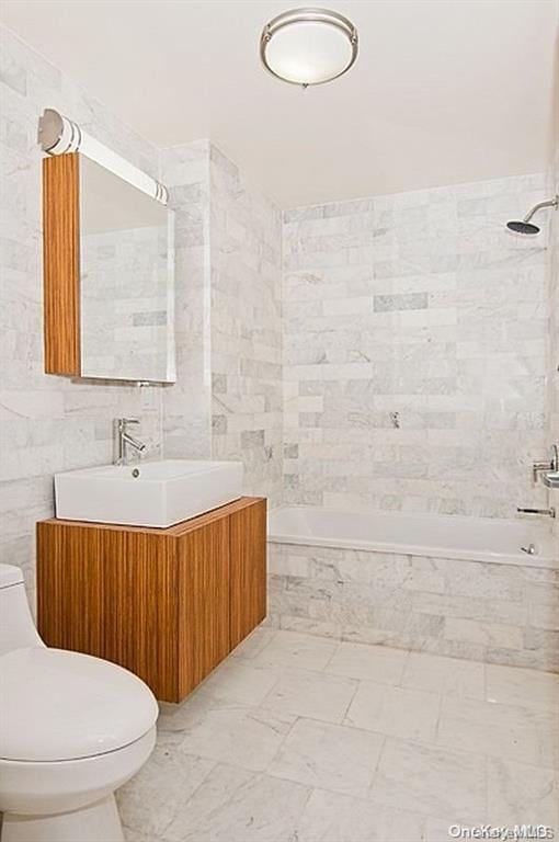 full bathroom featuring toilet, vanity, tile walls, and tiled shower / bath