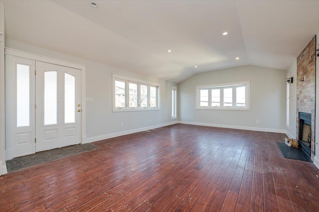 unfurnished living room featuring vaulted ceiling, dark hardwood / wood-style floors, and a brick fireplace