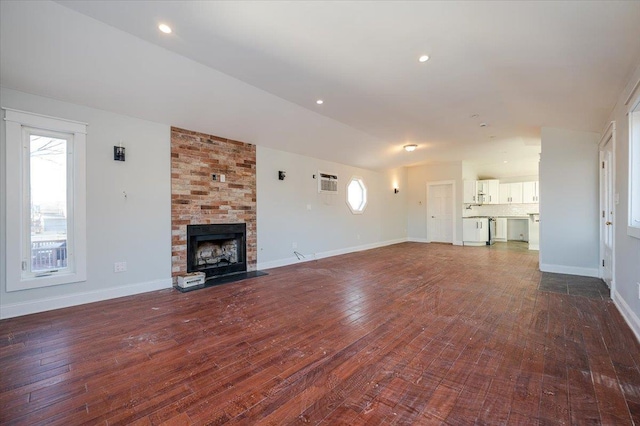 unfurnished living room with dark hardwood / wood-style flooring and a stone fireplace