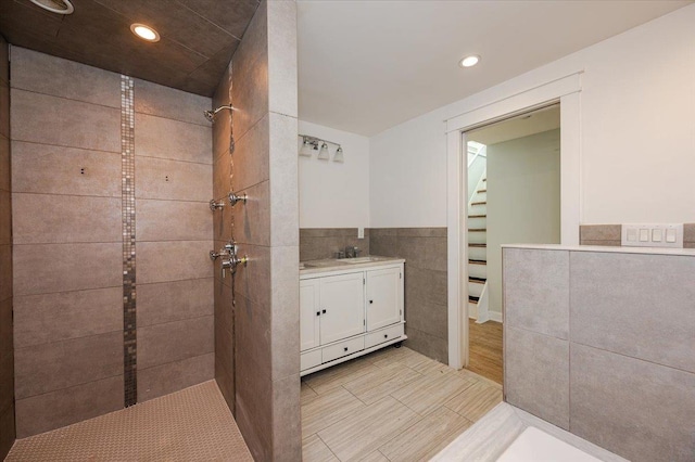 bathroom featuring tile patterned floors, vanity, a tile shower, and tile walls