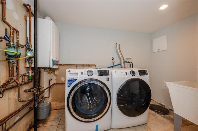 clothes washing area featuring independent washer and dryer, sink, light tile patterned floors, and water heater