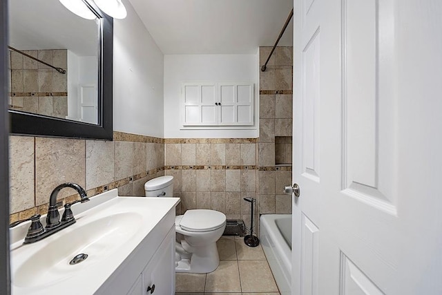 bathroom featuring toilet, tile patterned flooring, vanity, and tile walls