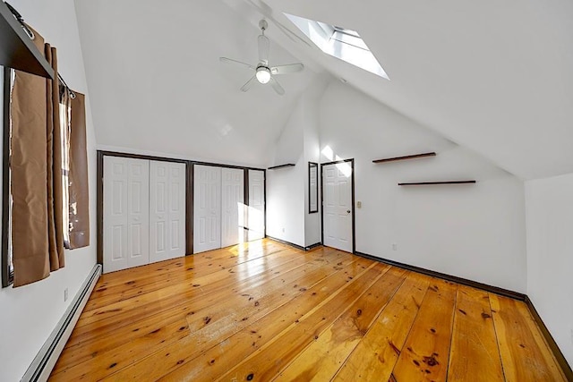 interior space with ceiling fan, light hardwood / wood-style floors, a baseboard heating unit, a skylight, and high vaulted ceiling