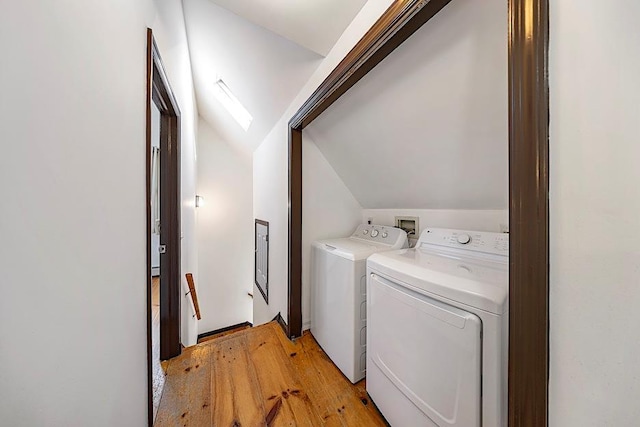 laundry room with light hardwood / wood-style floors, a skylight, and washer and clothes dryer