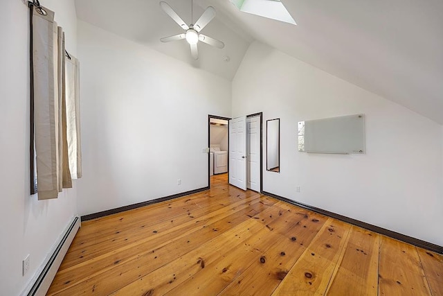 unfurnished bedroom with light hardwood / wood-style floors, ceiling fan, lofted ceiling with skylight, a baseboard heating unit, and washing machine and clothes dryer