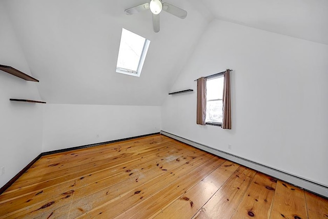 bonus room featuring lofted ceiling with skylight, wood-type flooring, baseboard heating, and ceiling fan