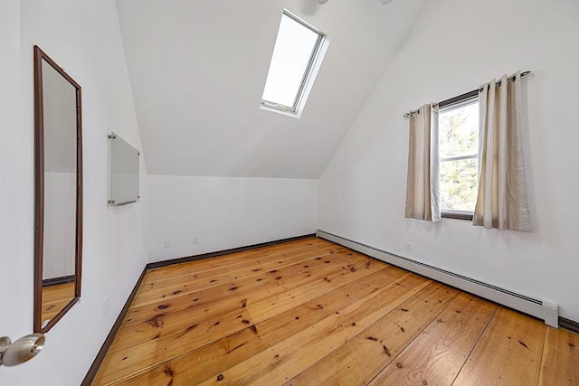 bonus room featuring wood-type flooring, vaulted ceiling with skylight, and a baseboard heating unit