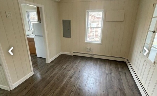 spare room with electric panel, dark wood-type flooring, a wealth of natural light, and a baseboard radiator