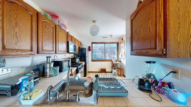 528 Barberry Ln, New Windsor, NY 12553 - kitchen with a sink, stainless steel microwave, tasteful backsplash, brown cabinetry, and tile countertops