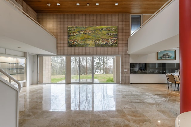 unfurnished living room with a towering ceiling and wooden ceiling