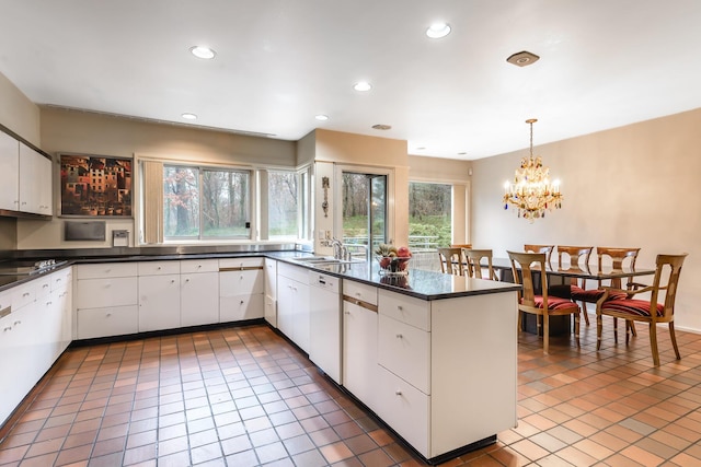 kitchen with white cabinetry, dishwasher, sink, hanging light fixtures, and dark tile patterned floors