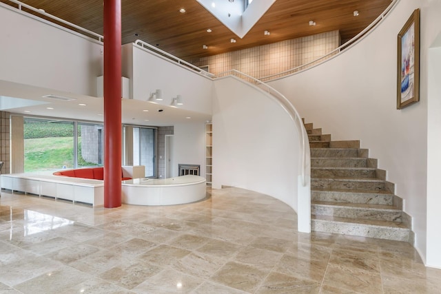 interior space with a towering ceiling, wood ceiling, and a skylight