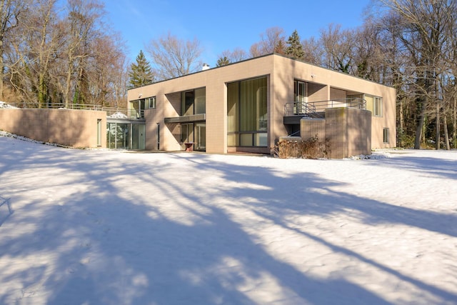 snow covered house featuring a balcony