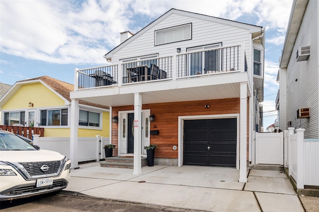 view of front of home with a garage, a balcony, and a wall unit AC