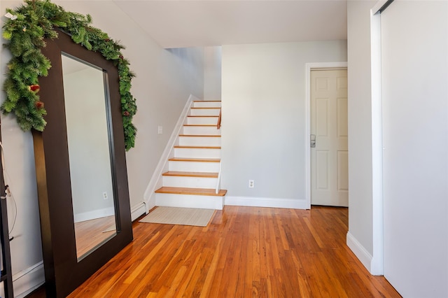 stairs with hardwood / wood-style flooring and a baseboard heating unit