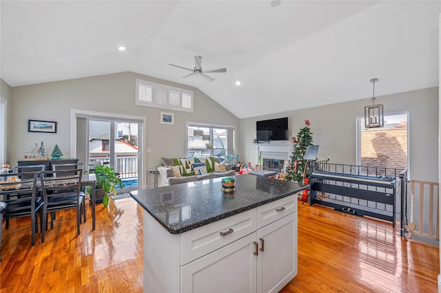 kitchen featuring light wood-type flooring, dark stone counters, ceiling fan, white cabinets, and a center island