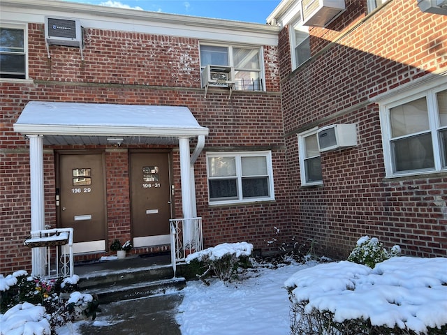 snow covered property entrance with cooling unit and an AC wall unit