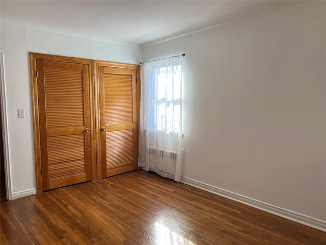 unfurnished bedroom with dark hardwood / wood-style flooring and a closet