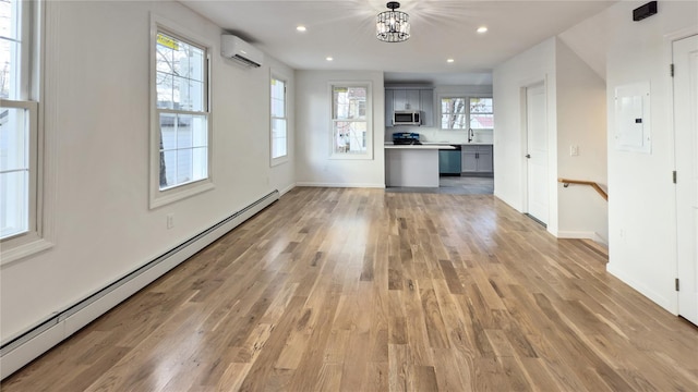 unfurnished living room featuring light hardwood / wood-style floors, a wall mounted AC, a baseboard radiator, an inviting chandelier, and electric panel