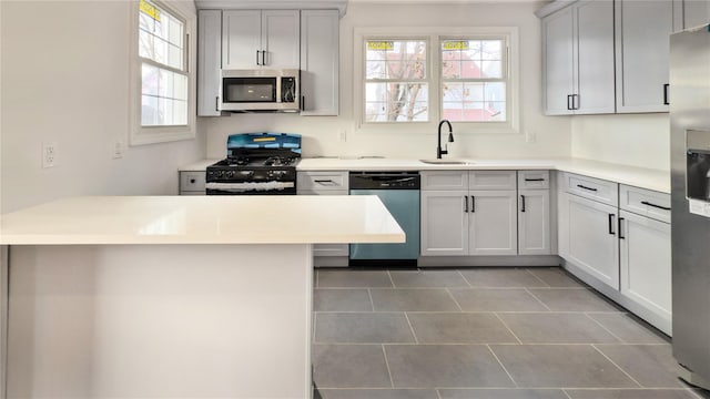 kitchen featuring sink, a breakfast bar area, light tile patterned floors, kitchen peninsula, and stainless steel appliances