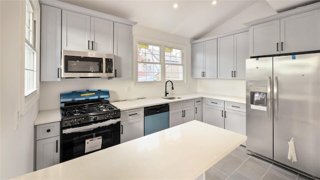 kitchen featuring sink, light tile patterned floors, stainless steel appliances, and lofted ceiling