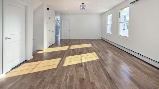 empty room featuring hardwood / wood-style floors, a baseboard heating unit, and a notable chandelier