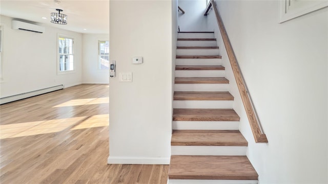 staircase featuring baseboard heating, a wall mounted AC, hardwood / wood-style floors, and an inviting chandelier