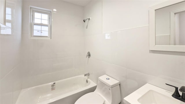 full bathroom with tiled shower / bath combo, toilet, sink, and tile walls