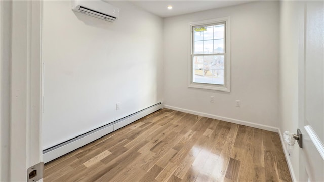 unfurnished room featuring an AC wall unit, light hardwood / wood-style flooring, and baseboard heating