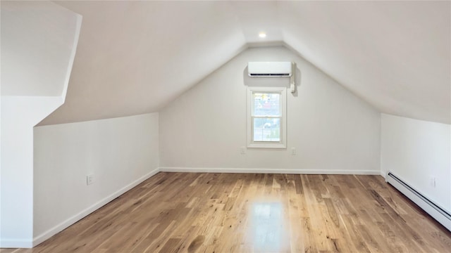 additional living space featuring a wall mounted air conditioner, vaulted ceiling, light wood-type flooring, and a baseboard radiator