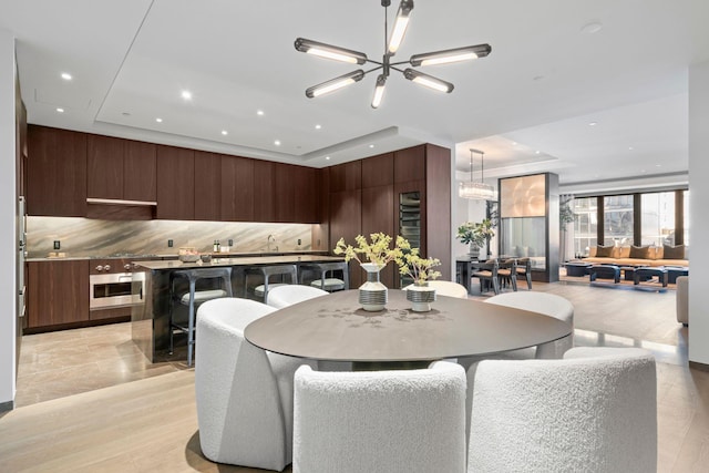 dining area with an inviting chandelier, a raised ceiling, and recessed lighting