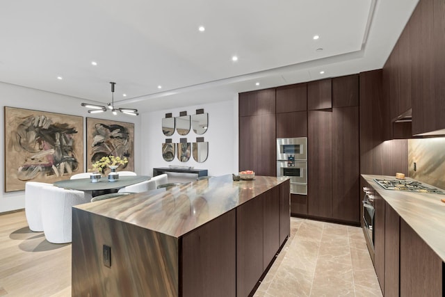 kitchen featuring stainless steel gas cooktop, recessed lighting, a kitchen island, dark brown cabinets, and modern cabinets