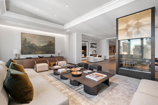 living area featuring recessed lighting, a raised ceiling, and wood finished floors